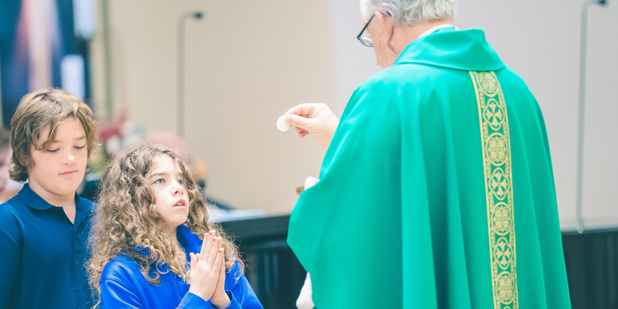 SJB students receiving Communion from priest